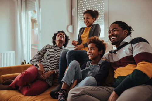 Mom, dad and two young kids laughing on a couch