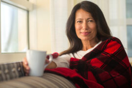 Woman holding mug and wearing checkered shaw