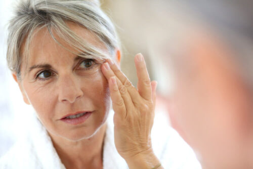 Older woman looks at winkles in mirror